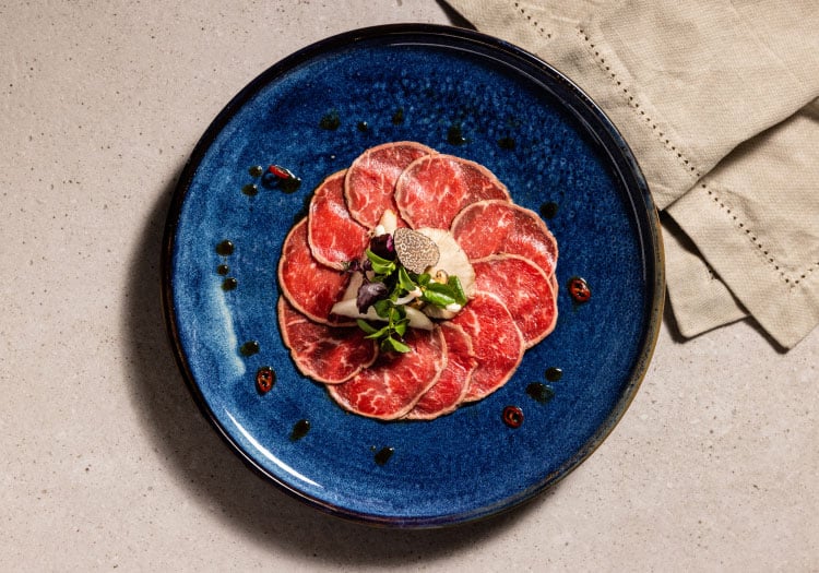 Beef Carpaccio plated on a blue plate
